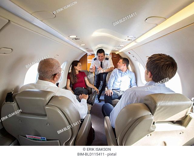 Pilot talking to business people on airplane