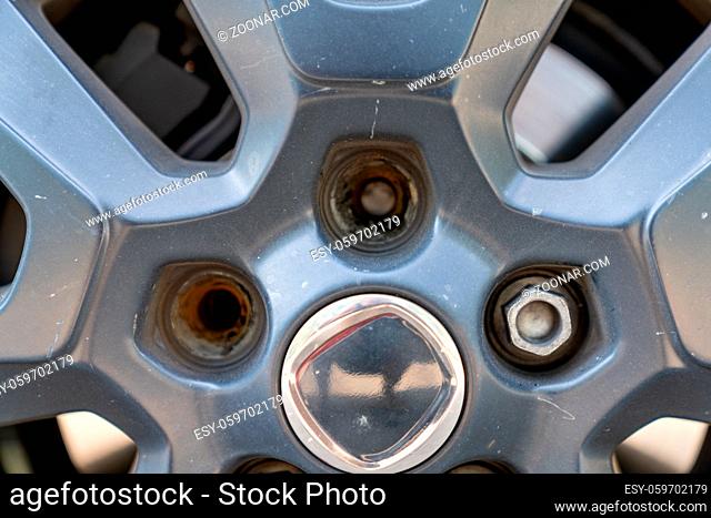 A close up view of the rim and wheel of a car with two broken lug nuts