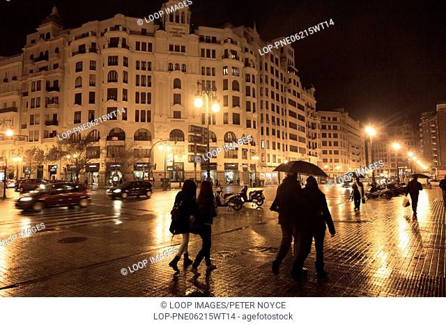 People under umbrellas on a rainy night on the streets of Valencia in Spain