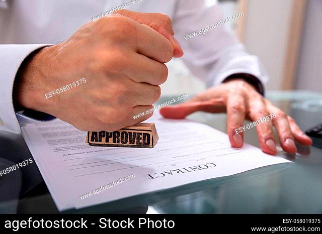 Businessman's Hand Stamping Approved On Contract Paper With Stamper