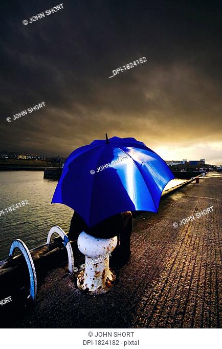 Person with umbrella in stormy skies