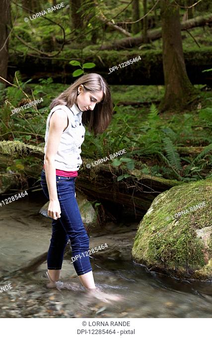Teenage girl walking barefoot in a stream; Chilliwack, British Columbia, Canada