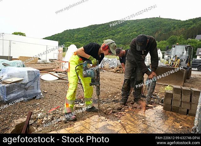 PRODUCTION - 08 June 2022, Rhineland-Palatinate, Dernau: Anny (l-r), Pompi and Dennis from ""Team Ballern"" lift away the remains of the foundation of a...