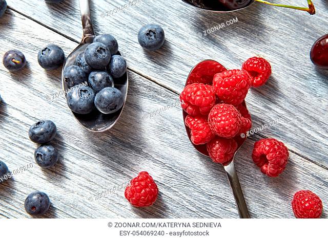 Delicious sweet berries on a spoon gray wooden background. Flat lay. Concept of vegetarian eating