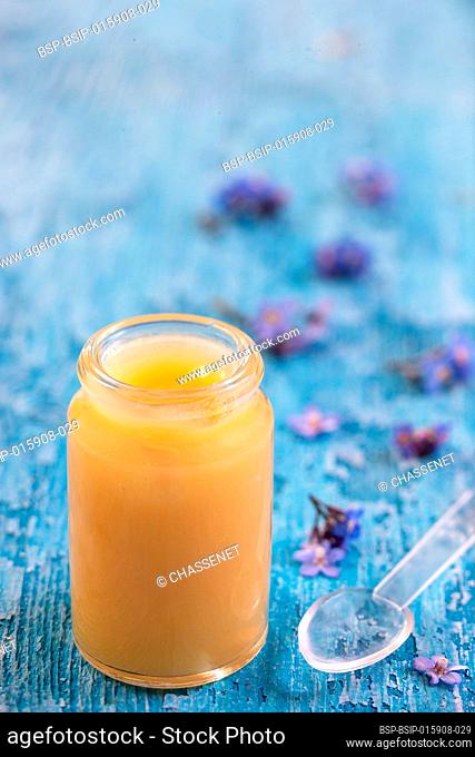 Organic royal jelly in a small bottle with flowers