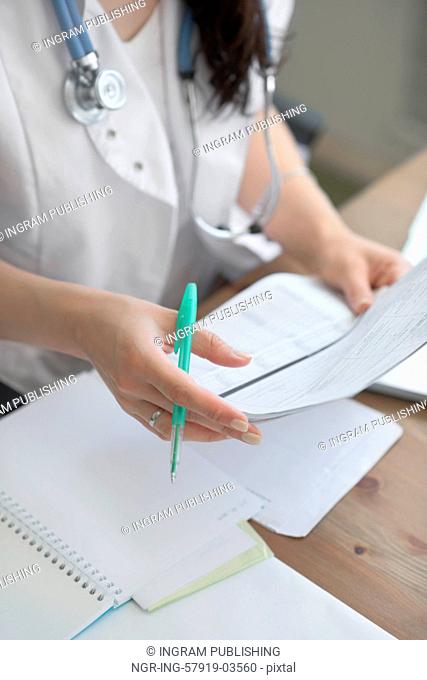 Female doctor taking notes during looking at patient medical tests at her office
