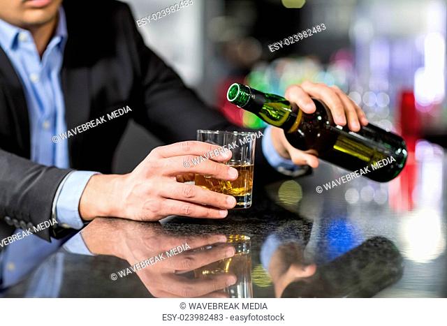 Businessman pouring whisky in glass