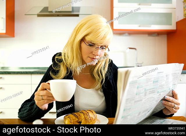 Woman having breakfast, reading the classifieds