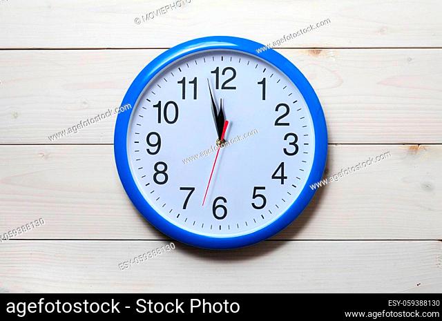 Blue wall clock with midnight new year time on wooden background