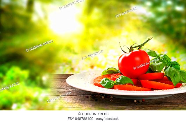 Fresh caprese salad on old rustic wooden table in a sunny garden scenery