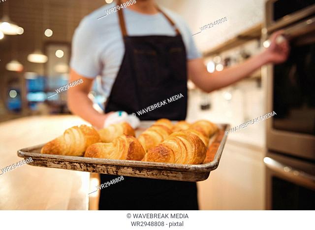 Barista holding tray of freshly baked croissants