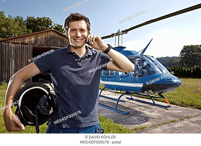 Germany, Bavaria, Landshut, Helicopter pilot using mobile phone