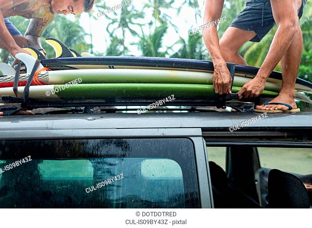 Men loading surfboards onto car roof rack, Pagudpud, Ilocos Norte, Philippines