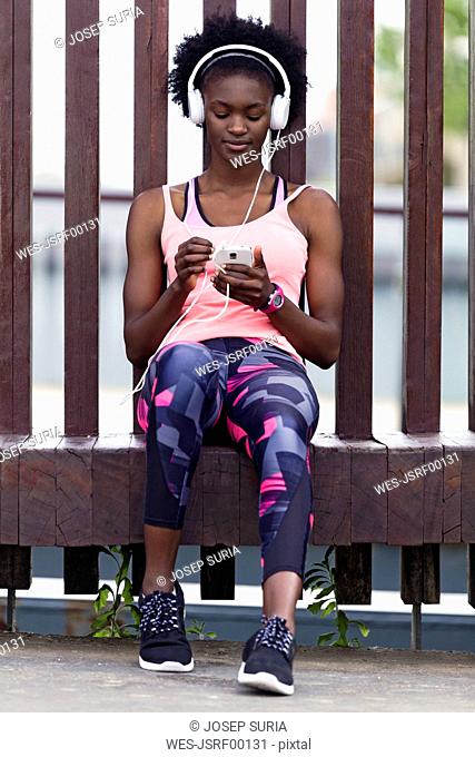 Sporty young women relaxing with headphones and cell phone