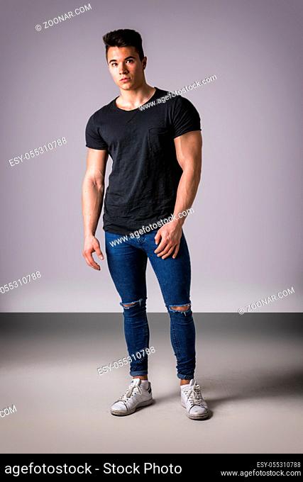Handsome young muscular man looking at camera in studio shot over neutral background. full length body shot