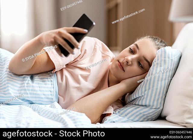 girl with smartphone in bed at home