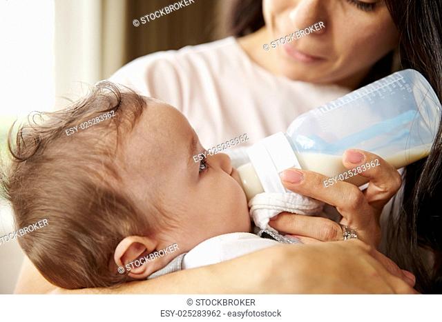 Mother Feeding Baby Boy From Bottle At Home