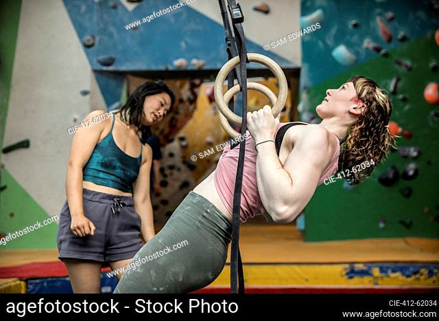 Young woman exercising at gymnastics rings in climbing center