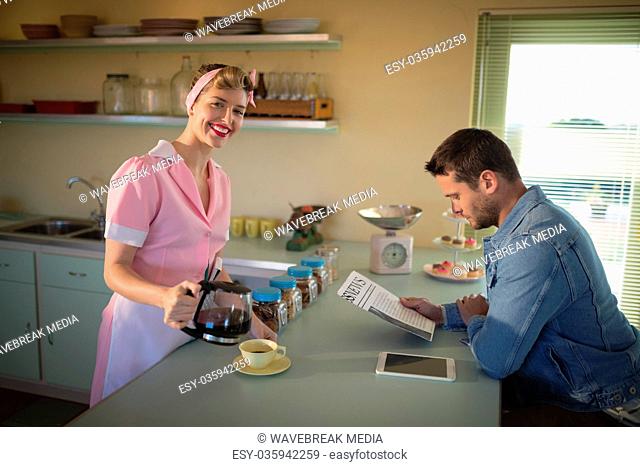 Waitress serving black coffee while man reading newspaper
