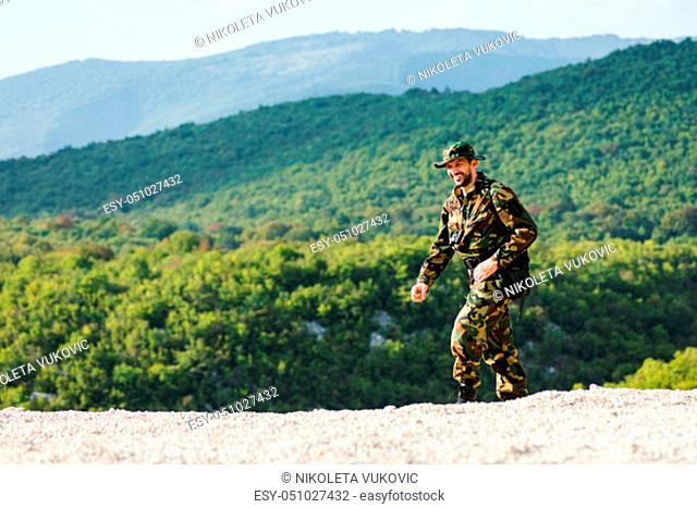 The smiling man in military uniform is walking and enjoying in the nature, adventure and journey concept