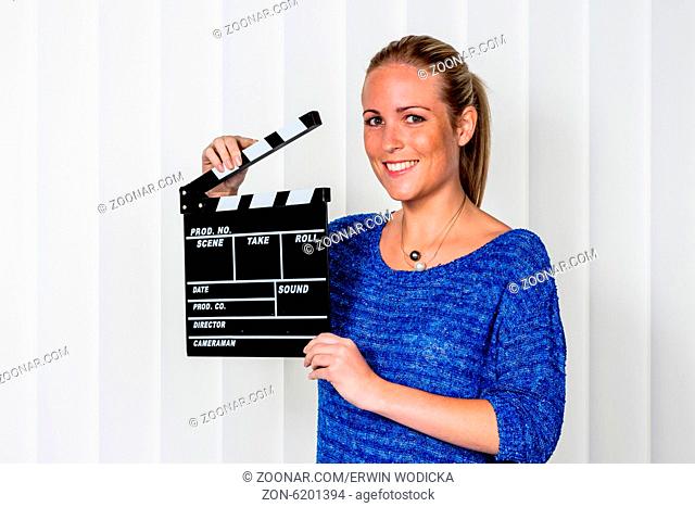 Eine Frau hält eine typische Filmklappe in ihrer Hand
