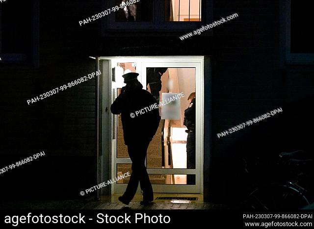 07 March 2023, Brandenburg, Senftenberg: Police officers stand in the hallway of an apartment building and in front of the front door