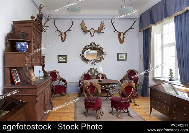 Traditional furniture and hunting trophies, carved chest of drawers, wall plaques and chairs and table made from deer antlers