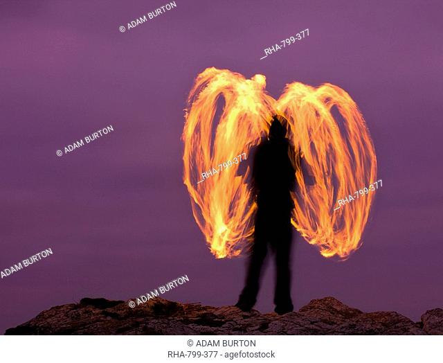 Man fire spinning Fire Poi on Cornish clifftops, Godrevy, Cornwall, England, United Kingdom, Europe