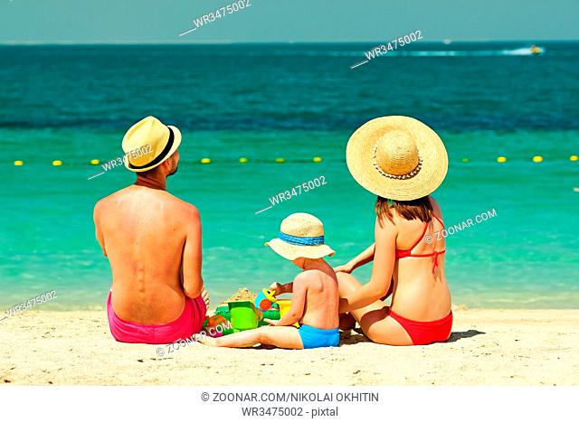 Family on beach. Two year old toddler boy playing with beach toys with mother and father on beach