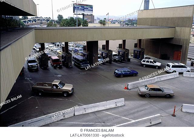 The control point for crossing on the border between USA and Mexico, with cars on road in queues