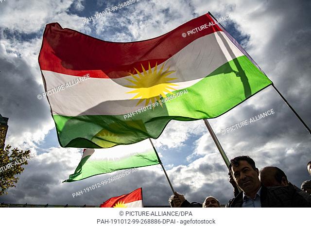 12 October 2019, Berlin: Demonstrators protest against the Turkish military offensive in Northern Syria with flags of the Autonomous Region of Kurdistan on...