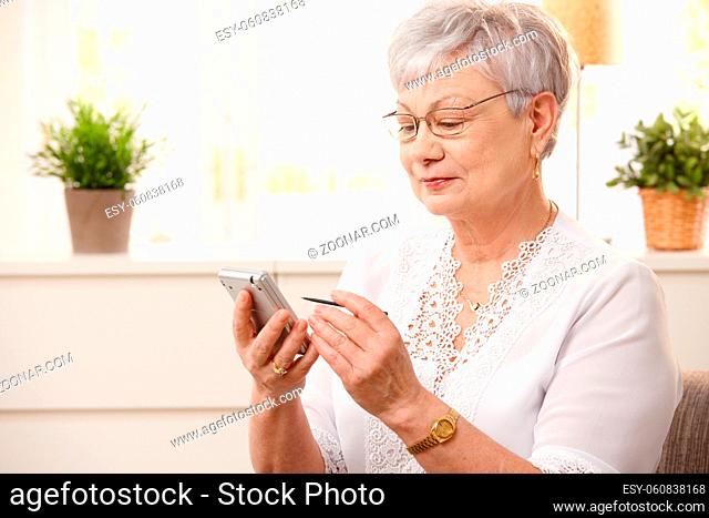 Portrait of modern senior woman using pda at home, smiling