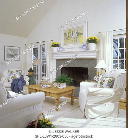 LIVING ROOMS - White on white, slip covers on overstuffed furnishings, fireplace, sliding glass doors on either side. Oak coffee table, curtains on French doors