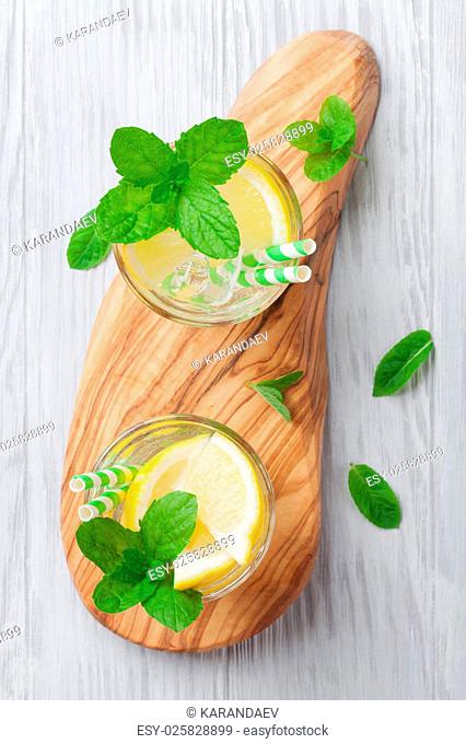 Lemonade glasses with lemon, mint and ice on wooden table. Top view