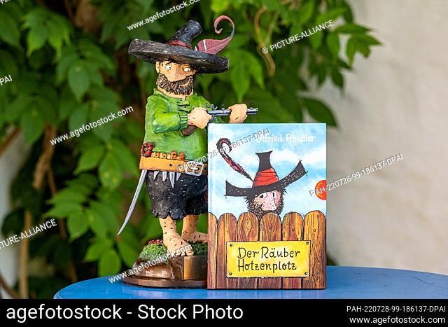 28 July 2022, Bavaria, Regen: The book ""The robber Hotzenplotz"" stands next to a figure of the robber. A pointed hat with a feather