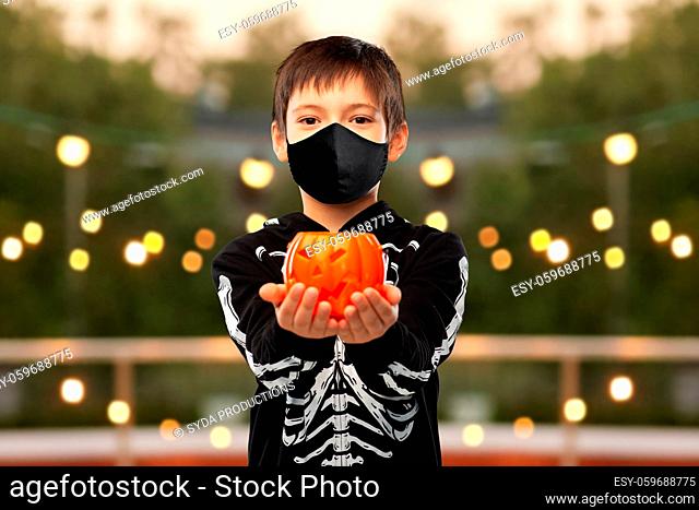 boy in mask and halloween costume with pumpkin