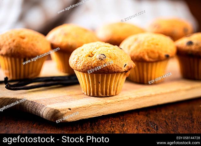 Vanilla muffins. Sweet cupcakes and vanilla pods on wooden table