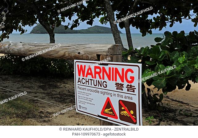 The coast and seaside resort Palm Cove in the tropical northeast of Australia - a sign on the beach indicates the danger of crocodiles and bathing prohibition...