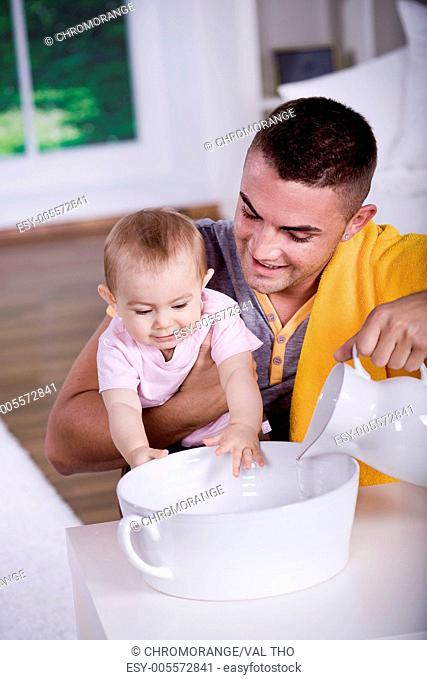 parents washing the small baby in the bathtub
