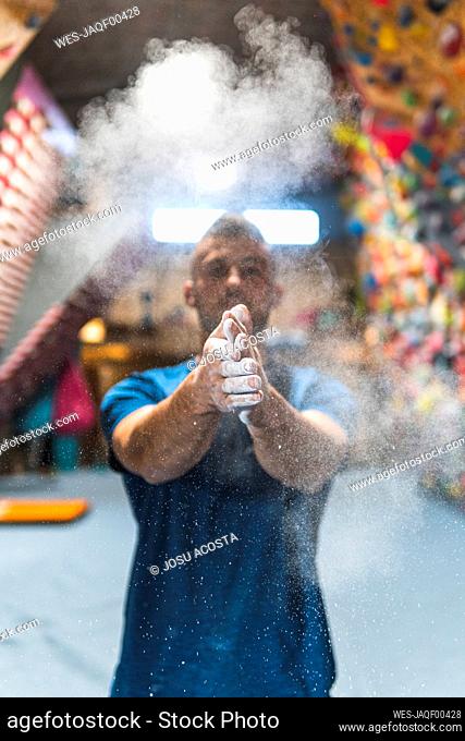 Young sportsman dusting talcum powder on hands in health club