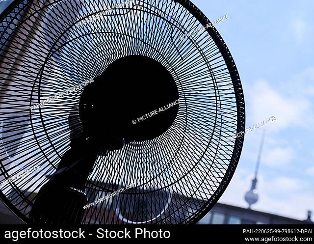 25 June 2022, Berlin: In one apartment, the fan is running outside the window near the TV tower. There is sultry heat in Berlin on the weekend