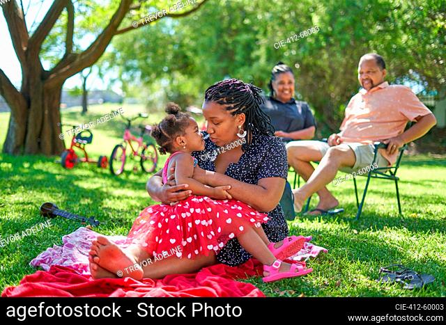 Affectionate mother and daughter relaxing in summer park