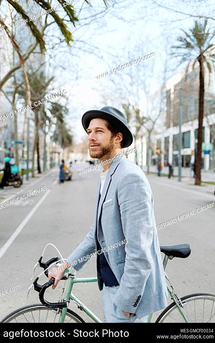 Businessman with bicycle walking in city while looking away