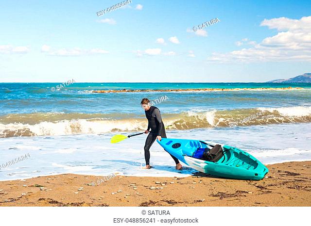 Young handsome man carrying kayak at sea beach