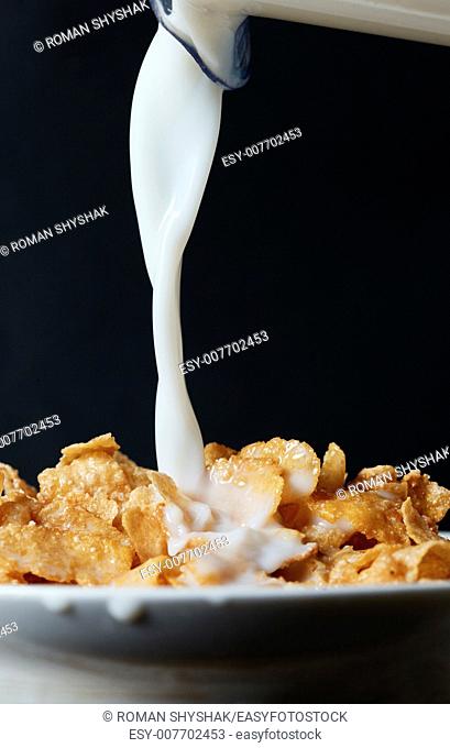 Corn flakes breakfast with milk being poured over it