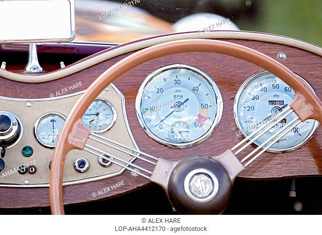 A close up view of the steering wheel and dashboard of a classic car at Goodwood revival