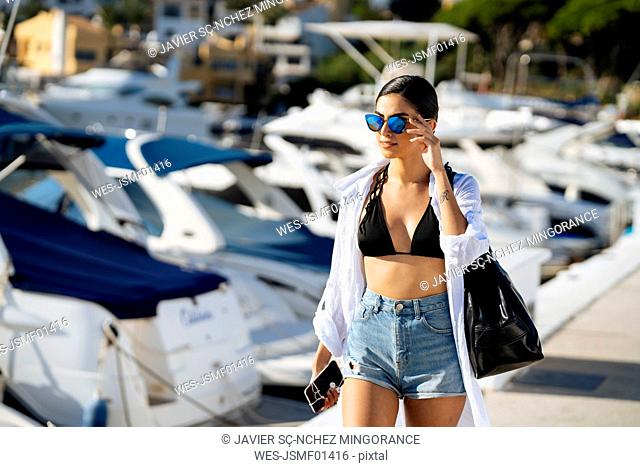 Young woman with a bag walking at a marina