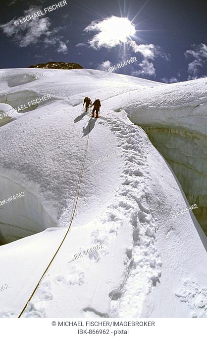 Two mountaineers crossing a big crevasse during an ascent of Mount Piz Glueschaint, Bernina Range, Graubuenden Canton, Switzerland, Europe