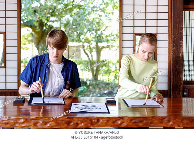 Caucasian couple practicing calligraphy at traditional Japanese house