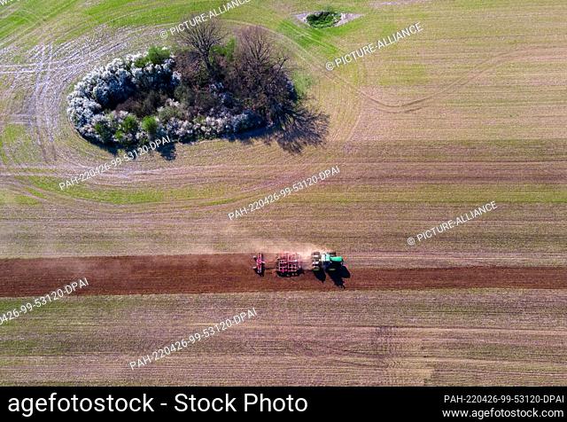 26 April 2022, Mecklenburg-Western Pomerania, Pokrent: A tractor pulls a harrow across a field in preparation for spring sowing